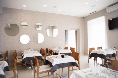 un restaurante con mesas blancas, sillas y espejos en FAIAS - Boutique Hotel, en Luanda