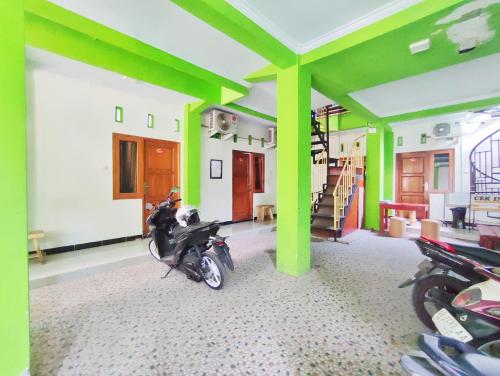 una motocicleta estacionada en una habitación con columnas verdes en Happy Syariah Hotel near Jombor Mitra RedDoorz, en Sleman