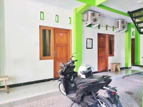 una motocicleta estacionada en una habitación con paredes verdes y blancas en Happy Syariah Hotel near Jombor Mitra RedDoorz, en Sleman