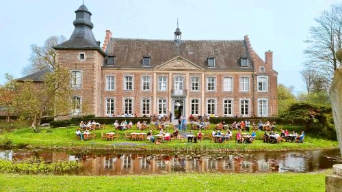 duży budynek z ludźmi siedzącymi przy stolikach przed nim w obiekcie Château de Looz w mieście Borgloon