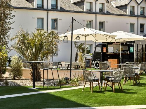 d'une terrasse avec des tables, des chaises et un parasol. dans l'établissement ibis La Roche Sur Yon Vendespace, à Mouilleron-le-Captif