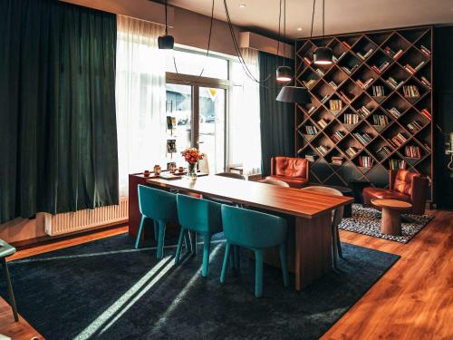 a dining room with a wooden table and blue chairs at ibis Styles Wałbrzych in Wałbrzych