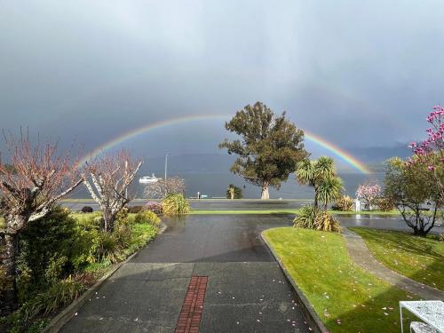 Un arcobaleno nel cielo sopra una strada con un vialetto di Fiordland Lakeview Motel and Apartments a Te Anau