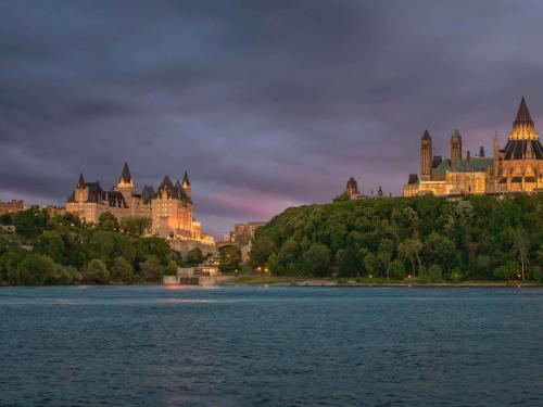 ein Schloss auf einem Hügel neben einem Wasserkörper in der Unterkunft Fairmont Chateau Laurier in Ottawa