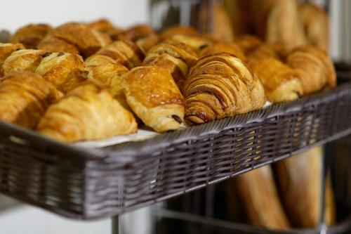 um monte de croissants e outros bolos num cesto em Hotel Douglas em Puteaux