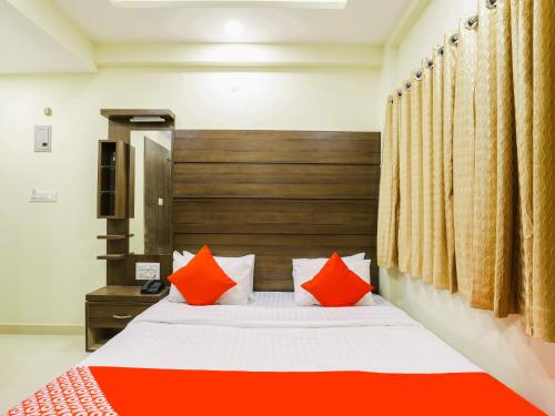 ein Schlafzimmer mit einem Bett mit orangefarbenen Kissen in der Unterkunft StayGuru Hotel Atithi in Bhuj