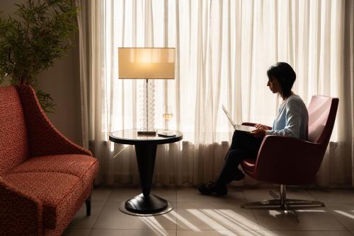 a woman sitting in a chair with a laptop in a room at Hotel American Palace Eur in Rome