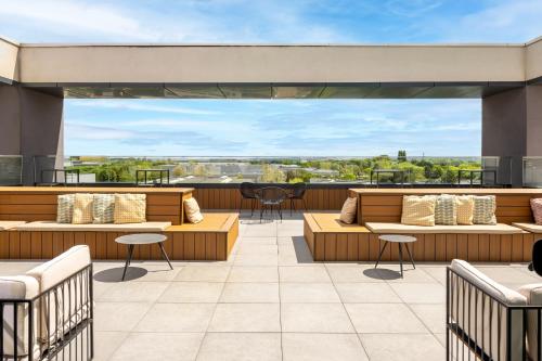 un patio avec des canapés et des tables sur le toit dans l'établissement Hyatt Place Paris Charles de Gaulle Airport, à Roissy-en-France