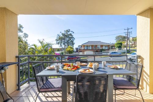 a table with plates of food on a balcony at Starfish Lodge, 2-1a Messines St - pet friendly, air con and Wi-Fi in Shoal Bay