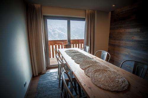 een lange houten tafel met stoelen en een groot raam bij La Cresta Chalet in Breuil-Cervinia