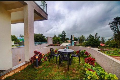 d'une table et de chaises sur un balcon fleuri dans l'établissement OCEAN CREST LUXURY VILLA Mahabaleshwar, à Mahabaleshwar