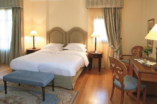 een slaapkamer met een groot wit bed en een bureau bij The Captain's House Boutique Hotel in Preveza