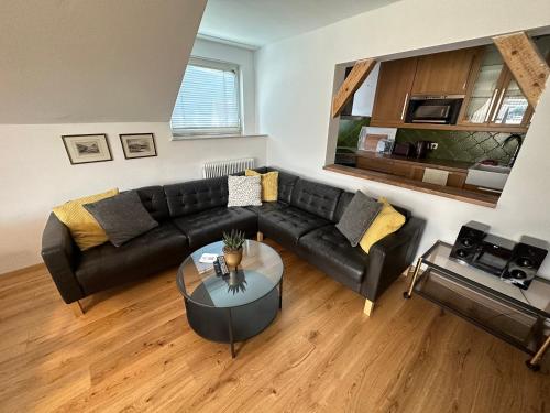 a living room with a black couch and a table at Nannerls Penthouse in Sankt Gilgen