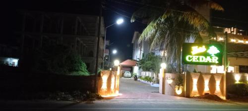 een bord voor een café in een straat 's nachts bij Hotel Cedar in Jaffna