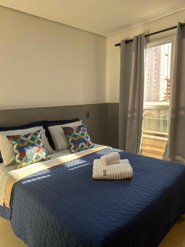 een slaapkamer met een blauw bed met 2 handdoeken erop bij Studio 303 - Extraordinário in Ribeirão Preto