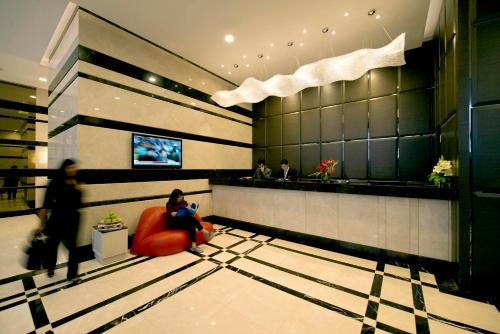 a lobby with a woman sitting in a red chair at V Hotel Bencoolen in Singapore