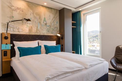 een hotelkamer met een groot bed met blauwe kussens bij Motel One Freiburg in Freiburg im Breisgau