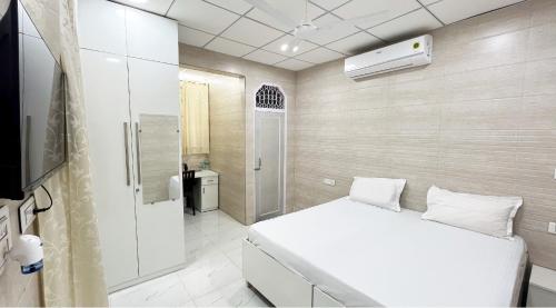 een slaapkamer met een wit bed en een badkamer bij Divya Anubhuti Pravas in New Delhi