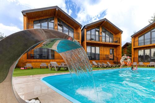 a pool with a water slide in front of a house at Hotel Pid Strihoju in Bukovel