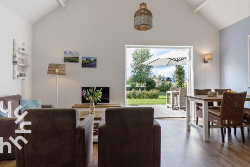 een woonkamer met een tafel en stoelen en een parasol bij OV072 Exklusives 4P-Ferienhaus in bester Lage in Giethoorn in Giethoorn