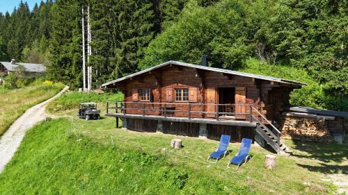 uma cabana de madeira com duas cadeiras azuis em frente em Chalet d'alpage avec vue incroyable em Saint-Gervais-les-Bains