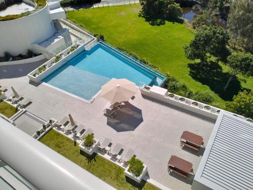 einen Blick über einen Pool mit Stühlen und einem Sonnenschirm in der Unterkunft Kirra Surf Apartments in Gold Coast