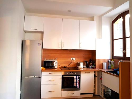 a kitchen with white cabinets and a stainless steel refrigerator at BIG FLAT - LE CALA - Hypercentre - 4 chambres, 13 personnes, proche plage gare et parking, WIFI, Air Conditioning l GROUPE l BUSINESS l FAMILLE in Nice