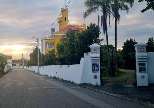 un bâtiment jaune avec une clôture blanche en face d'une rue dans l'établissement Vila Aurora, à Luso