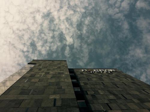 ein hohes Gebäude mit wolkigem Himmel im Hintergrund in der Unterkunft Harbor Hotel in Jeju-do