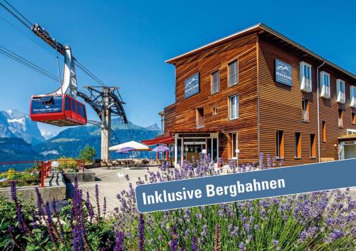 a ski lift in front of a building with purple flowers at Hotel Panorama in Hasliberg