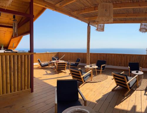 a deck with chairs and tables and the ocean at Casa Boha in Dhërmi