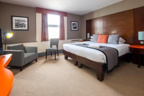 a hotel room with a large bed and a chair at Sheffield Metropolitan Hotel in Sheffield