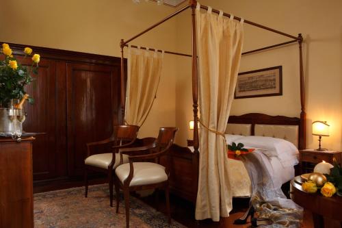 um quarto com uma cama de dossel, uma mesa e cadeiras em Pensione Accademia - Villa Maravege em Veneza