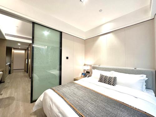 - une chambre avec un grand lit et un mur en verre dans l'établissement CM Serviced Apartment Shenzhen Dongmen, à Shenzhen