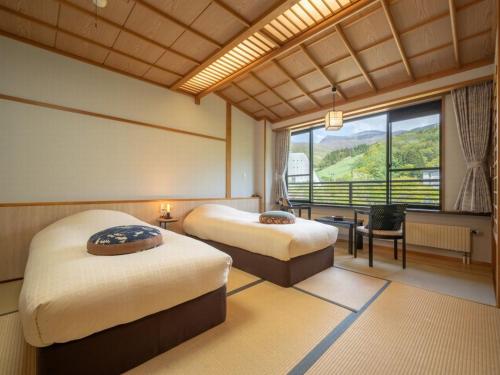 ein Hotelzimmer mit 2 Betten und einem Fenster in der Unterkunft 蔵王温泉 岩清水料理の宿 季の里 in Zao Onsen