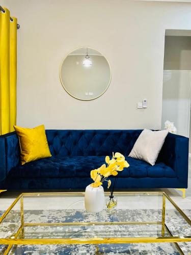 um sofá azul numa sala de estar com almofadas amarelas em Alchemy Luxury Apartments em Gaborone