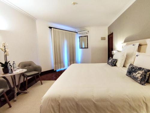 a hotel room with a large bed and a table at Luso Village Boutique Hotel in Luso