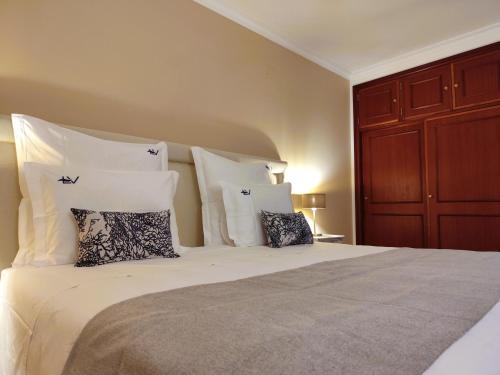 a bedroom with a large bed with white pillows at Luso Village Boutique Hotel in Luso