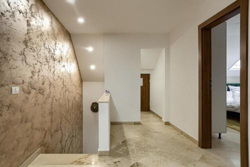 un corridoio con pareti bianche e un muro in pietra di Sika Palladium Garden & Spa Central Apartment Arad a Arad