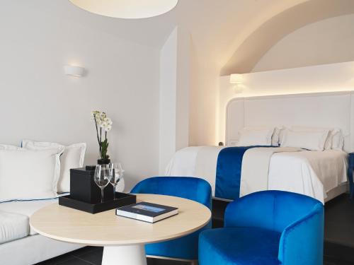 a hotel room with two beds and a table and chairs at Katikies Santorini - The Leading Hotels Of The World in Oia