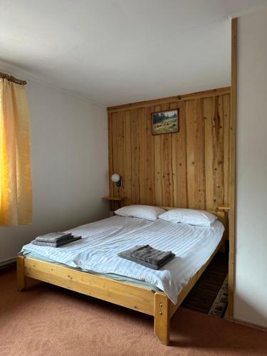 1 dormitorio con 1 cama con pared de madera en Plai, en Dragobrat