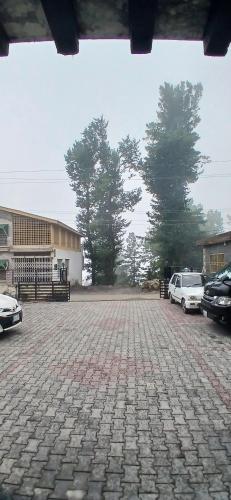 a brick parking lot with cars parked in front of a building at 62hills hotel ayubia in Ayubia