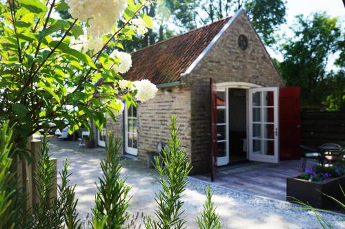 una casa in mattoni con una porta rossa e un patio di B&B Piebengastate Welsrijp a Welsrijp