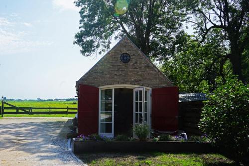 una piccola casa con un orologio sopra di B&B Piebengastate Welsrijp a Welsrijp