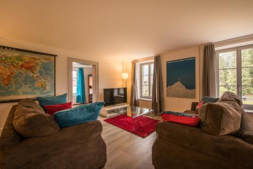 a living room with two couches and a tv at Dependance Penthouse in Interlaken