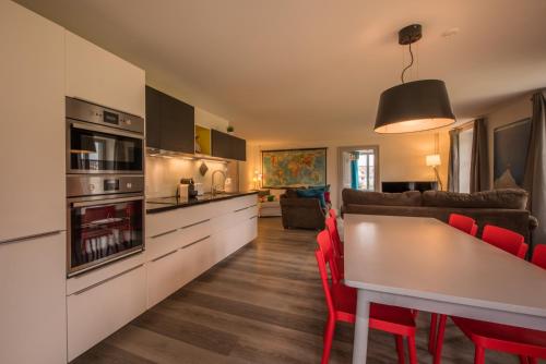 a kitchen and living room with a table and red chairs at Dependance Penthouse in Interlaken