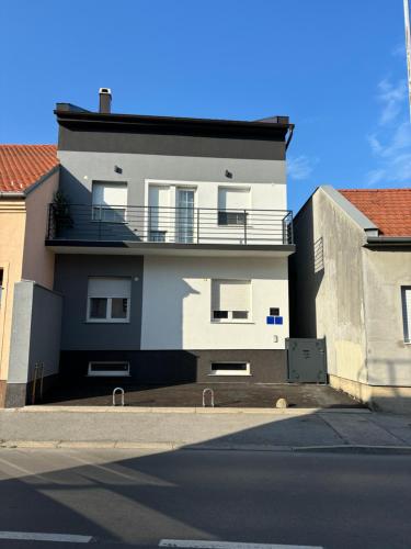 een wit gebouw met een balkon aan de straatkant bij Vila Galerija in Vukovar