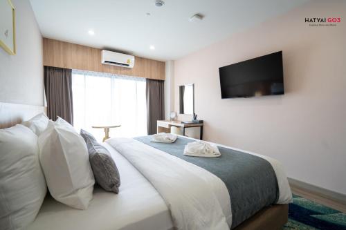 a bedroom with a large bed with a television on the wall at Chinatown Living Hatyai in Hat Yai