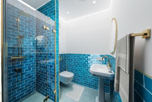 bagno piastrellato blu con servizi igienici e lavandino di Magazin Rooms a Salisburgo