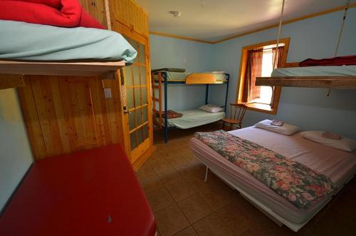 a bedroom with two bunk beds and a red bench at Auberge jeunesse de Tadoussac in Tadoussac